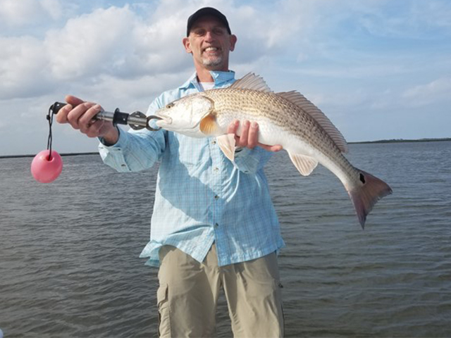 Amelia Island Backwater Fishing, John proudly displays a great 25-inch Redfish weighing about 6 pounds.