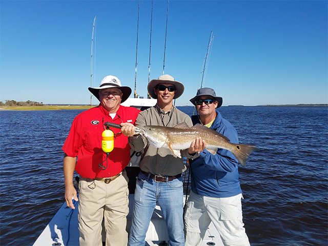Three men hold up their Redfish caught on Fernandina Beach Fishing Charter